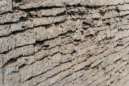 The wall of an old fortress made of pieces of natural stone as a background.