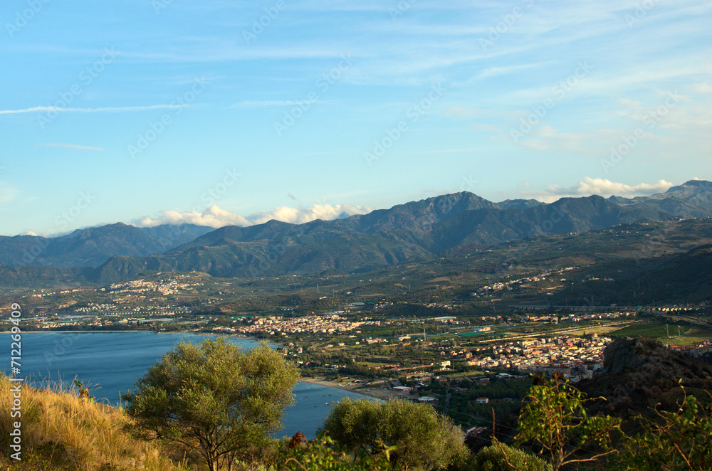 Picturesque aerial landscape view of Tindary at sunny autumn day. City on the shore of The Mediterranean Sea. Majestic mountains in the background. Travel and tourism concept
