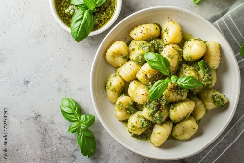 Italian dish of potato gnocchi topped with basil pesto served on a grey background photo