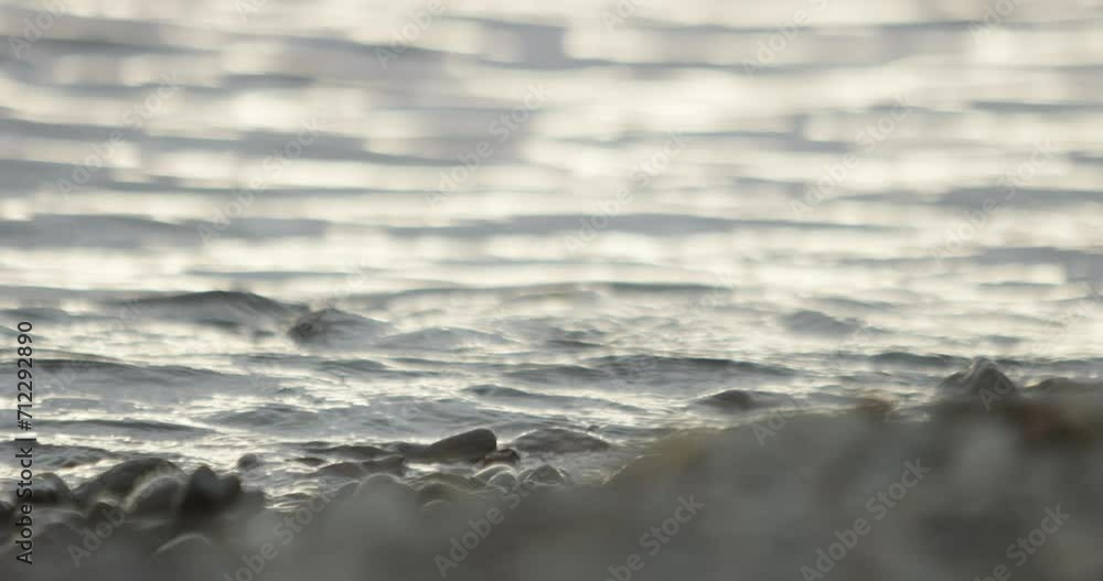 slow motion water texture gently flowing over a pebble on a rocky beach slow motion water texture gently flowing over a pebble on a rocky beach