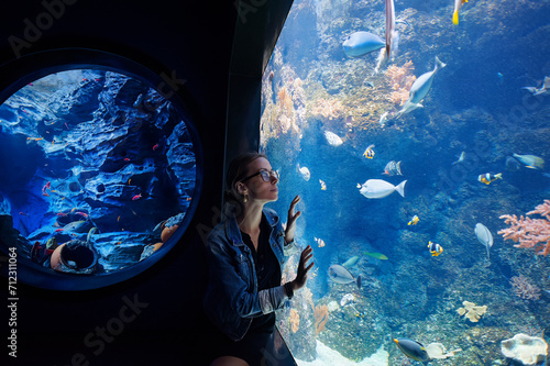 Photography Young woman looking at fishes in oceanarium