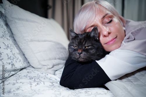 Young blode woman and her adorable black tabby cat. photo