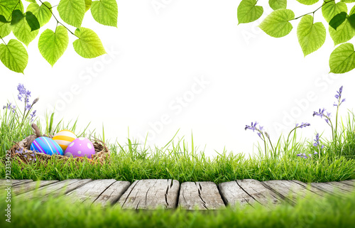 Obraz na płótnie A blank template of three painted easter eggs in a birds nest celebrating a Happy Easter with a wooden bench to place products on with green grass and tree leaves on a transparent background w salonie