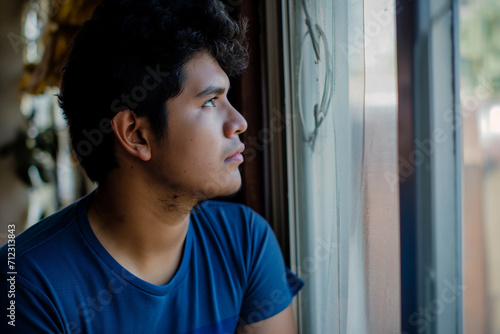 Um garoto venezuelano pensando olhando pela janela 