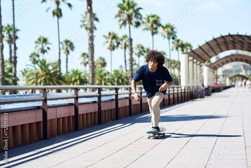 Boy sliding his skateboard along sunny sidewalk.
