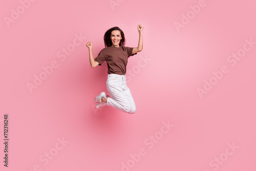 Full body length photo of energetic lady jumping raised fists up celebrating her awesome productivity isolated on pink color background © deagreez