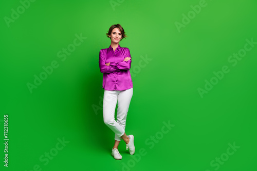 Full size portrait of stunning positive girl crossed arms posing empty space isolated on green color background