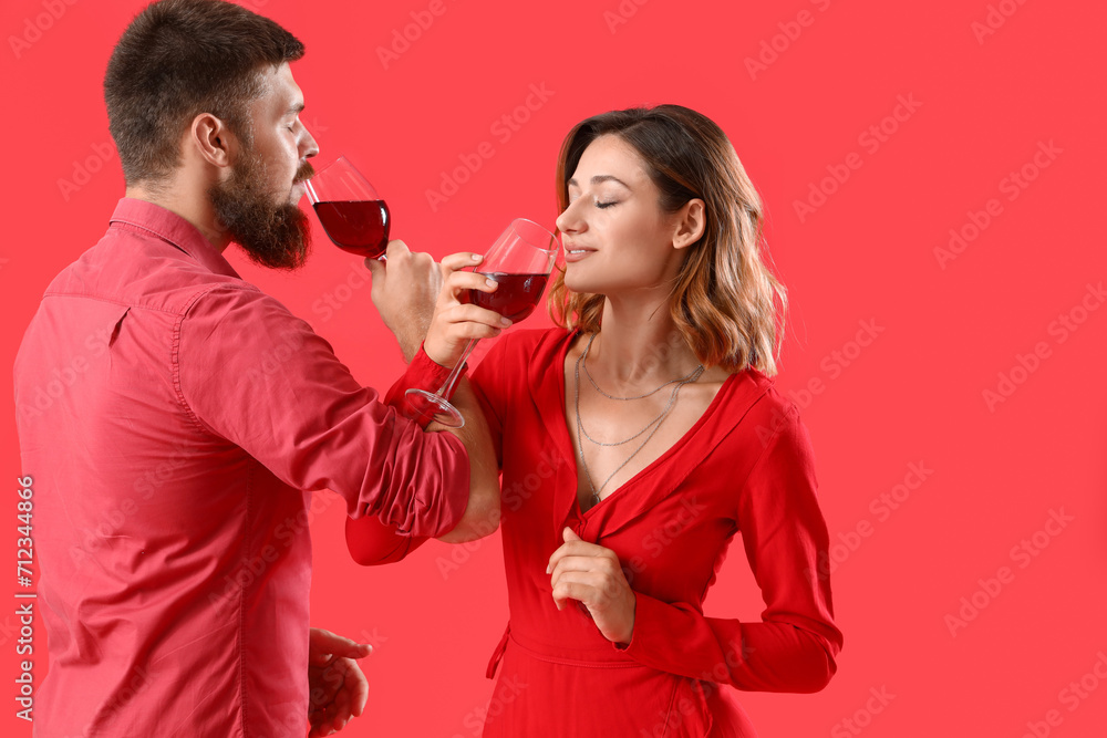 Happy couple in love with glasses of wine on red background Happy couple in love with glasses of wine on red background
