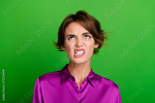 Photo of mad furious girl dressed trendy magenta clothes showing teeth look up empty space isolated on green color background © deagreez