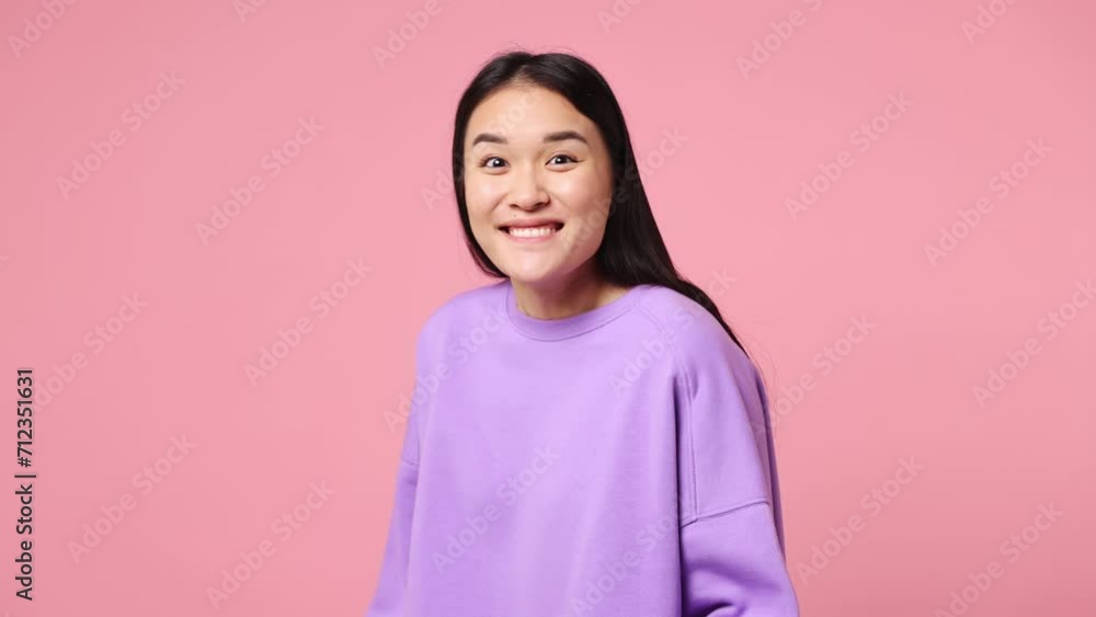 Side profile view surprised young woman of Asian ethnicity wear purple sweatshirt turn around camera spread hands say wow omg no way isolated on plain pastel light pink background. Lifestyle concept Side profile view surprised young woman of Asian ethnicity wear purple sweatshirt turn around camera spread hands say wow omg no way isolated on plain pastel light pink background. Lifestyle concept