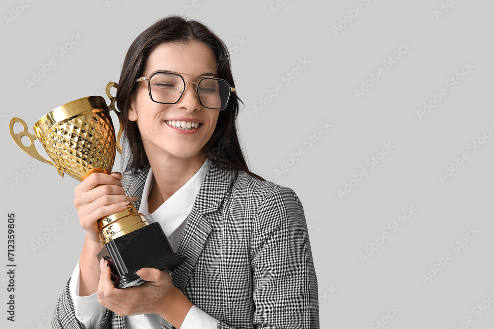 Young businesswoman with gold cup on light background Young businesswoman with gold cup on light background
