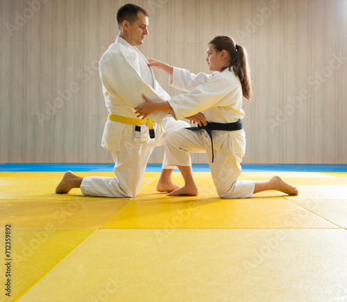 Yellow belt judo man and young black belt judo girl