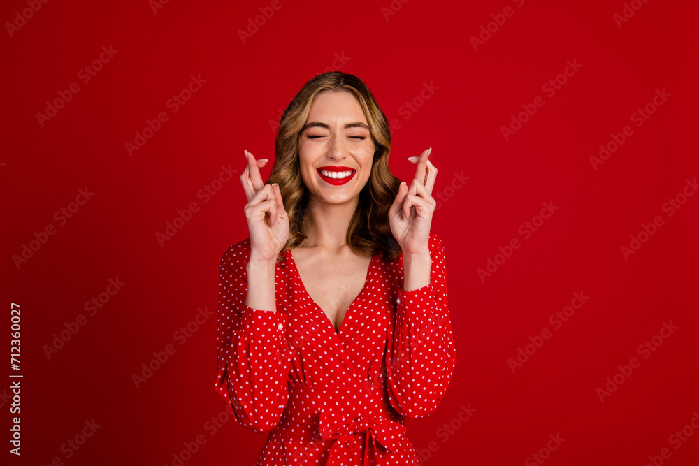Photo of pretty positive person closed eyes toothy smile crossed fingers wait expect isolated on red color background Photo of pretty positive person closed eyes toothy smile crossed fingers wait expect isolated on red color background