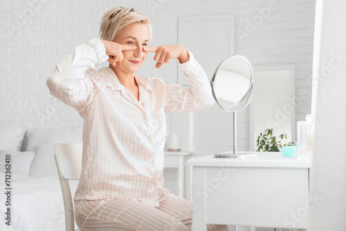 Mature woman doing face building exercise in bedroom photo
