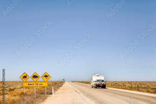 Nullarbor Plain, South Australia - Car and caravan on the Eyre Highway, Nullarbor Plain, including iconic sign look out for camels, kangaroos, wombats. This is called the Treeless Plain. photo