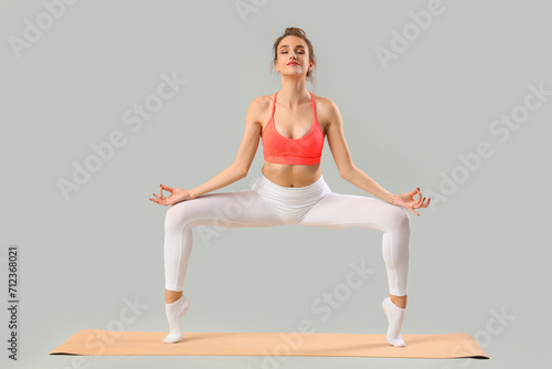 Young woman doing yoga on g...