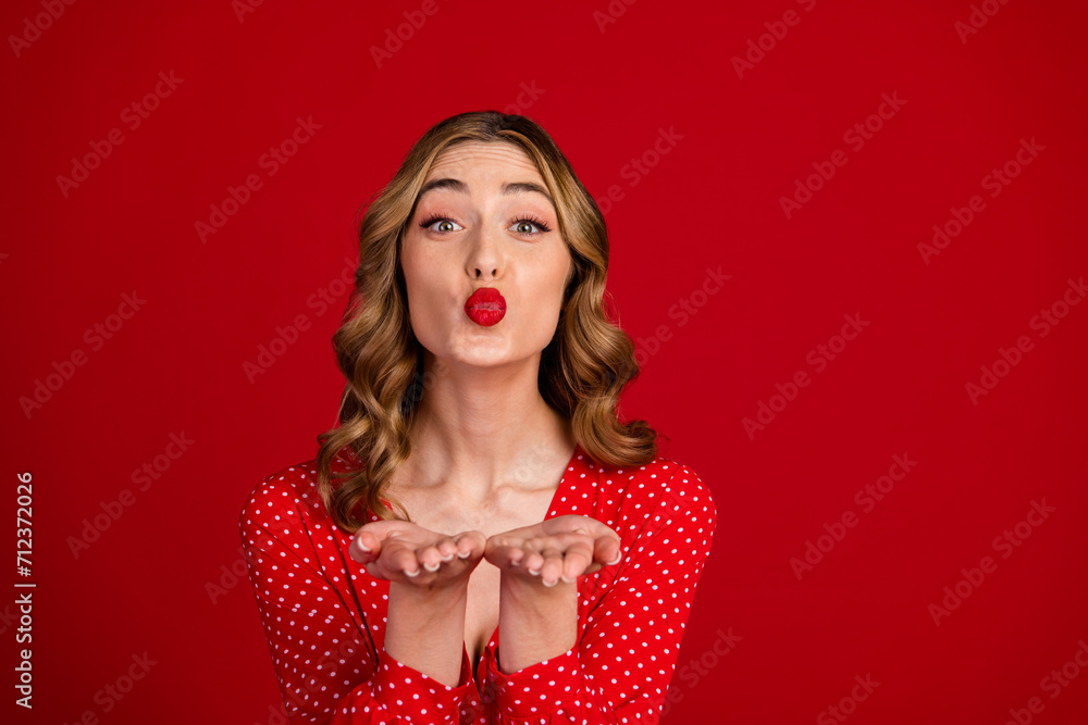 Photo of pretty gorgeous person pouted lips arms palms send air kiss you empty space isolated on red color background Photo of pretty gorgeous person pouted lips arms palms send air kiss you empty space isolated on red color background