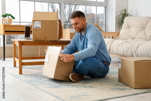 Young man unpacking parcel ...