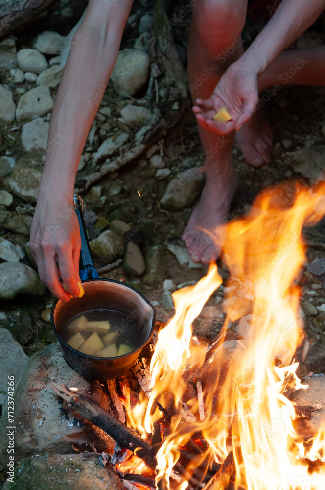 Female Adult Caucasian Hiker Preparing Herself Boiled Potatoes on a Camp Fire in Wilderness Female Adult Caucasian Hiker Preparing Herself Boiled Potatoes on a Camp Fire in Wilderness