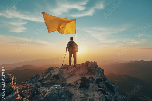 Atop a majestic peak, a triumphant traveler waves a vibrant yellow flag, symbolizing accomplishment and success in conquering life's challenging heights. photo