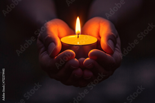 Hands holding a candle in the dark, depicting the concept of faith, hope, spirituality, or praying