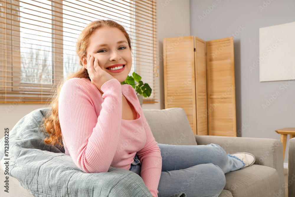 Smiling young redhead woman lying on sofa at home Smiling young redhead woman lying on sofa at home
