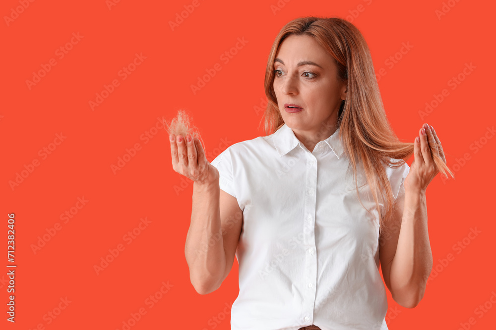 Worried mature woman with hair loss problem on red background Worried mature woman with hair loss problem on red background