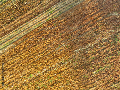 Aerial view of agriculture plowed field. Minimal tillage for healthier soils. Fertile soil in organic agricultural farm. Soil conservation. Sustainable agriculture. Soil fertility. Plowed land.