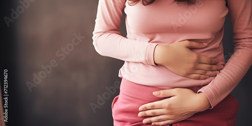 a woman holds her stomach with her hands and suffers from pain photo