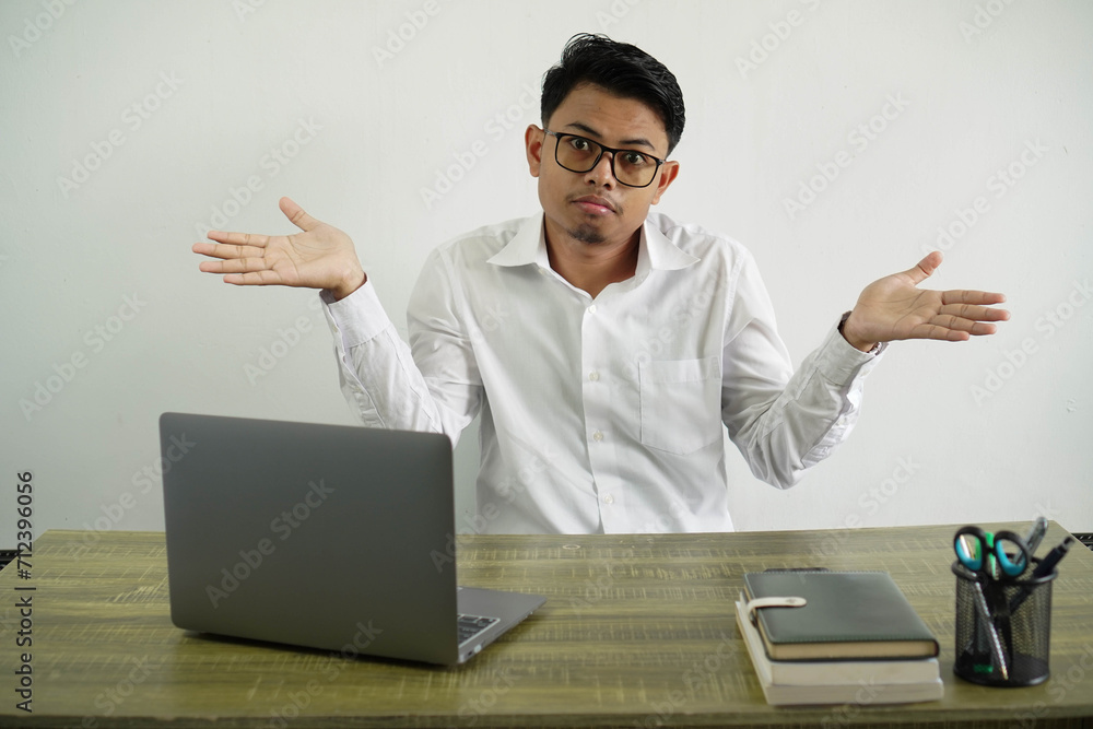 young asian businessman in a workplace having doubts while raising hands wearing white shirt with glasses isolated young asian businessman in a workplace having doubts while raising hands wearing white shirt with glasses isolated
