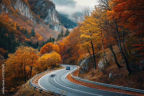 Winding mountain road trough the forest in the autumn with cars passing on the road