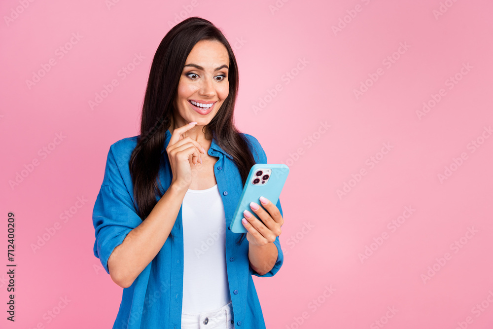 Photo of impressed girl with straight hairdo dressed blue shirt astonished staring at smartphone isolated on pink color background Photo of impressed girl with straight hairdo dressed blue shirt astonished staring at smartphone isolated on pink color background