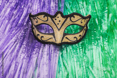 Half-face masks, Venetian. Costume for carnival ball and parties. Background of green and purple plastic strips.