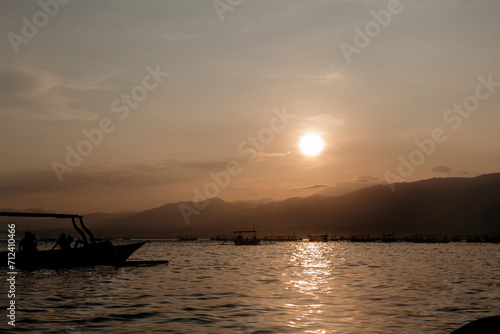 Fishing boats sail towards the island. Early morning and sunrise over the mountains