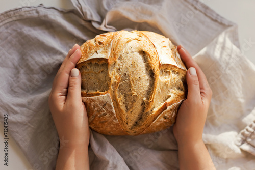 Woman holds freshly baked sourdough bread