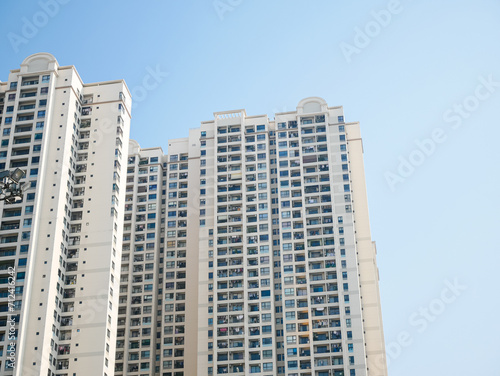 Looking up high-rise apartment complex condominium buildings with open balcony hanging clothes, clear blue sky in Hanoi, Vietnam, upscale expensive residence Asian urban real estate market