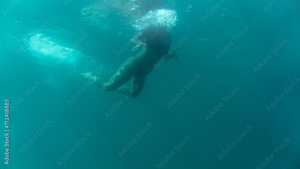 a girl swimming at sea. seen from below. 
