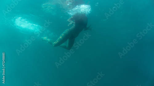 a girl swimming at sea. seen from below. 