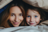 Portrait of smiling mother and daughter lying together in bed at home