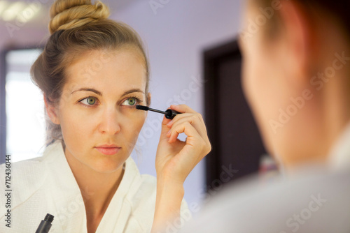 Woman applying make up looking at mirror