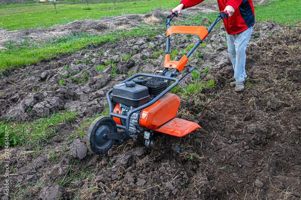 Obraz premium agricultural landscape transforms under the influence of a dedicated farmer and a robust motor cultivator, priming the soil for cultivation.