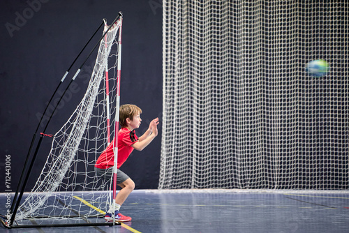 Détermination juvénile, enfant de huit ans gardien débutant arrêtant le ballon au handball