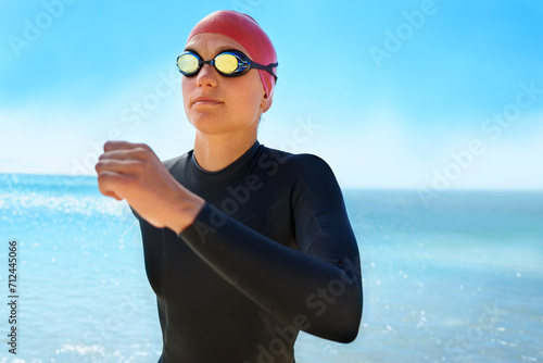 Fitness, goggles and woman swimming at the beach with blue sky for triathlon, race or competition training. Female Swimmer, athlete or person in ocean or sea for sports workout or exercise for health