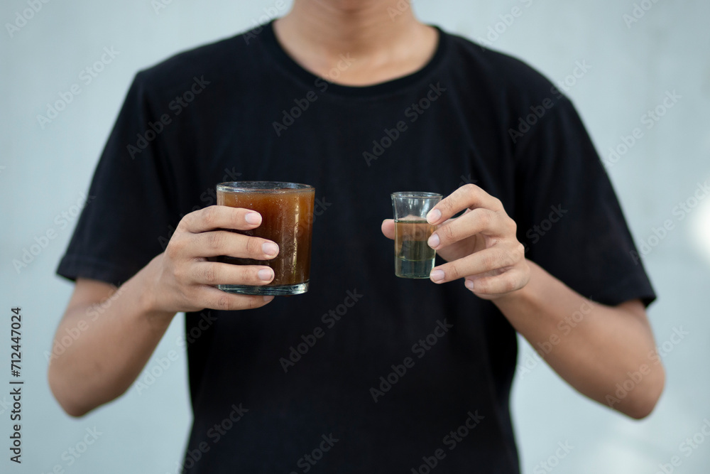 Front view close up of a man hands holding a coffee cup and liquid sugar at home Front view close up of a man hands holding a coffee cup and liquid sugar at home