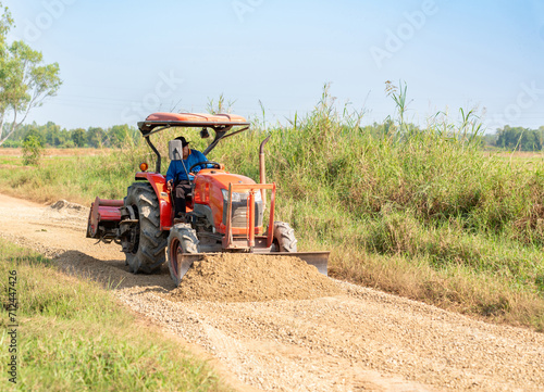 A stone-plowing tractor is leveling the road surface.