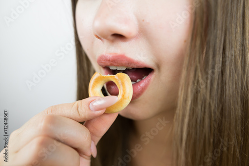 young beautiful girl eating bagels  close-up  crop photo.Attractive brunette sexy woman eating a delicious donut.