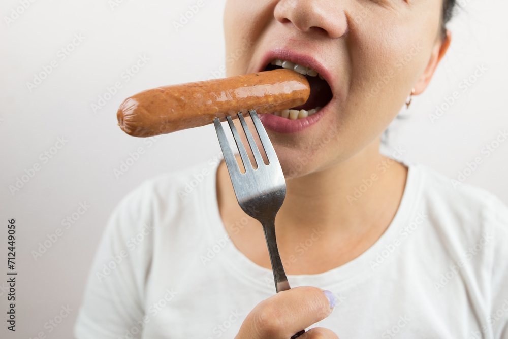woman eats sausage on a fork. Close-up. woman eats sausage on a fork. Close-up.