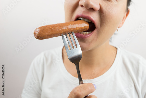 woman eats sausage on a fork. Close-up.