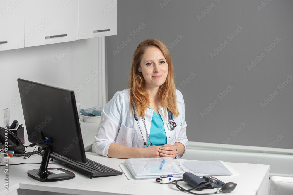 Portrait of young female medicine doctor sitting and working at her office. Healthcare and medical concept.Doctor in white coat doing paperwork at workplace with laptop, writing notes in the clinic. Portrait of young female medicine doctor sitting and working at her office. Healthcare and medical concept.Doctor in white coat doing paperwork at workplace with laptop, writing notes in the clinic.