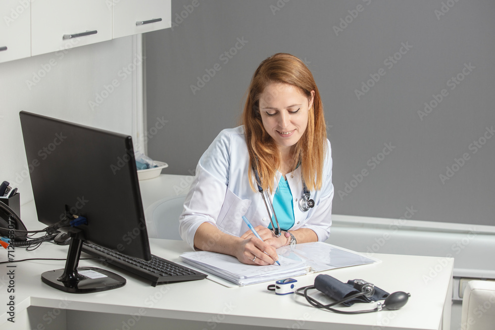Portrait of young female medicine doctor sitting and working at her office. Healthcare and medical concept.Doctor in white coat doing paperwork at workplace with laptop, writing notes in the clinic. Portrait of young female medicine doctor sitting and working at her office. Healthcare and medical concept.Doctor in white coat doing paperwork at workplace with laptop, writing notes in the clinic.